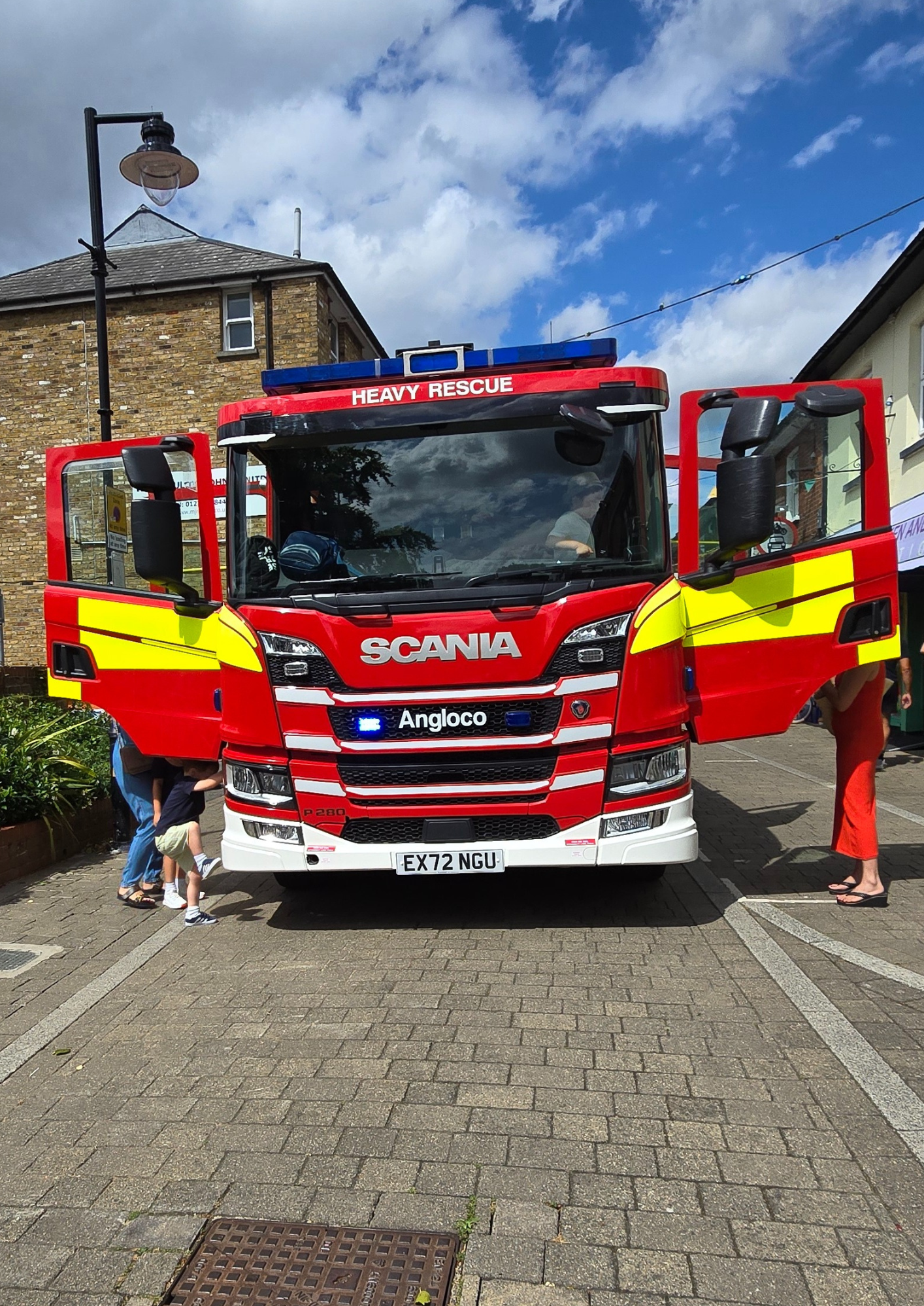 An image of a fire engine with its doors open and people exploring inside.