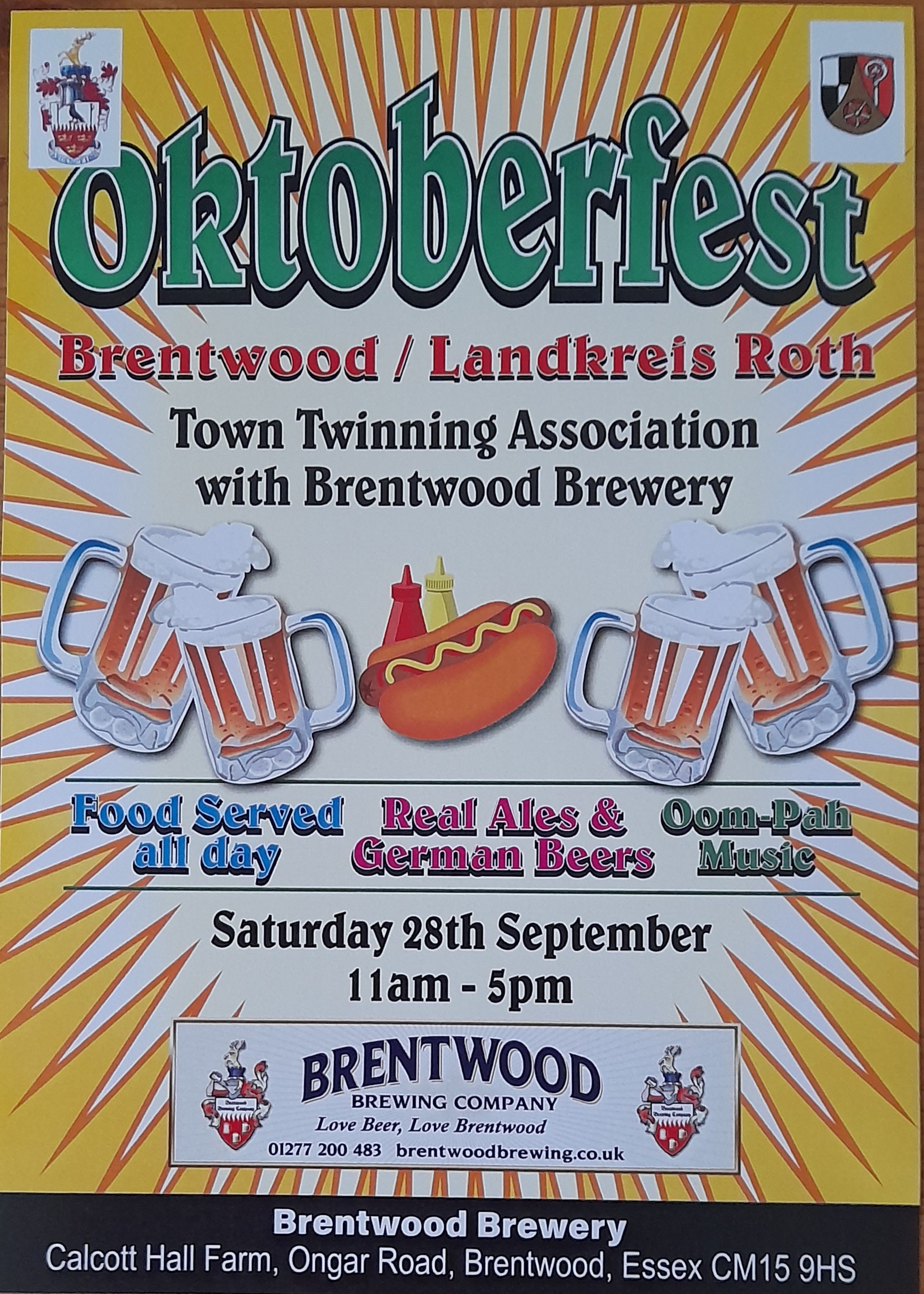 The image is a poster for an Oktoberfest event. The main text reads: "Oktoberfest Brentwood / Landkreis Roth" "Town Twinning Association with Brentwood Brewery" Below this, there are graphics of beer mugs, a hot dog with mustard and ketchup bottles, and more beer mugs. The text around the graphics says: "Food Served all day" (in blue text) "Real Ales & German Beers" (in red text) "Oom-Pah Music" (in green text) Further down, the details of the event are provided: "Saturday 28th September 11am - 5pm"