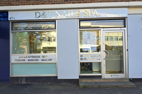 Exterior of D&T Nails Spa, a white sign with gold lettering.