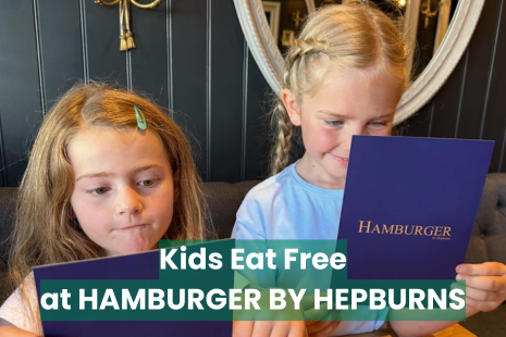 Image promoting a special offer from Hamburger by Hepburns.  Kids eat free, including a photo of two young girls looking at Hamburger by Hepburns menus.