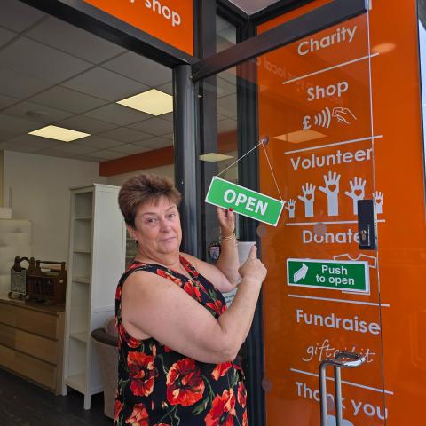 Image showing a member of staff at Saint Francis Hospice holding an 'OPEN' sign.