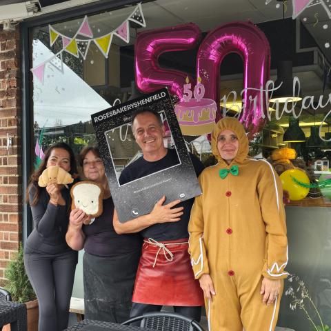 Image showing members of staff outside Roses Bakery with a balloon display celebrating their 50th birthday behind them.