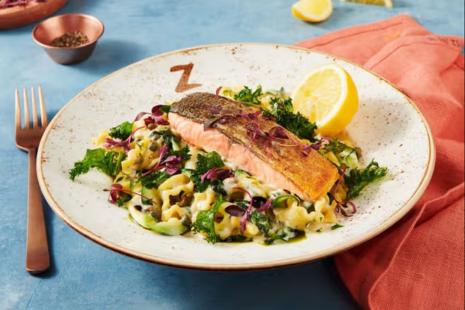 A bowl of salmon on pasta with a lemon. A 'Z' is printed on the bowl.